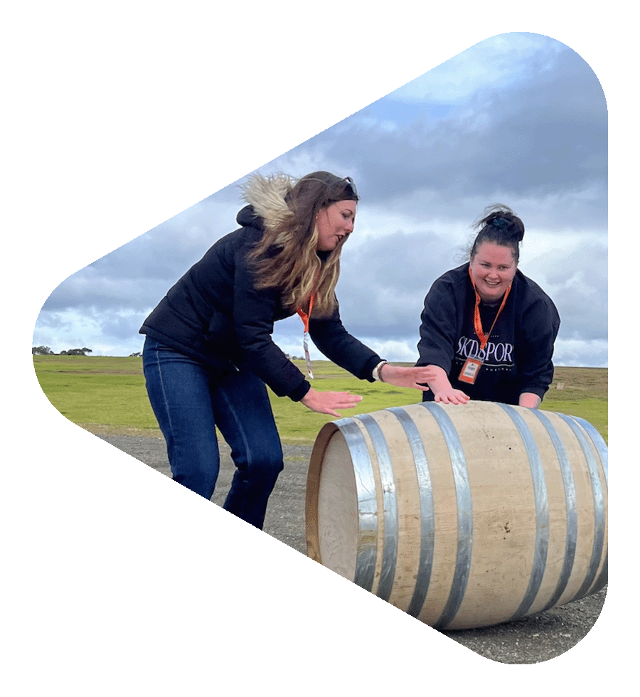 Team rolling barrels through a vineyard during a Hunter Valley team building challenge