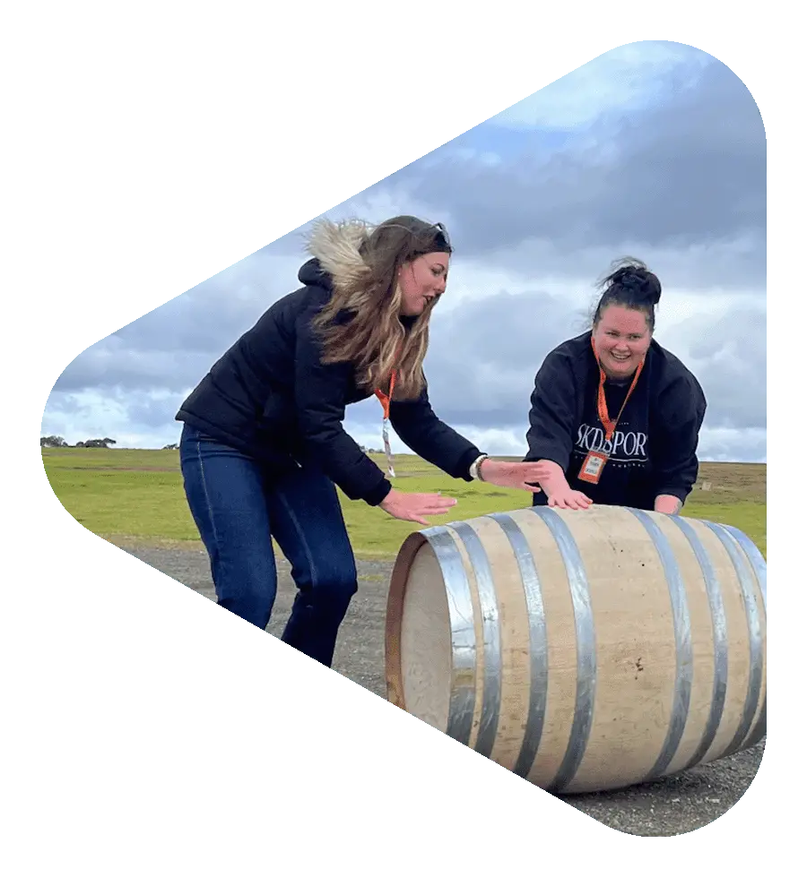 Team rolling barrels through a vineyard during a Hunter Valley team building challenge