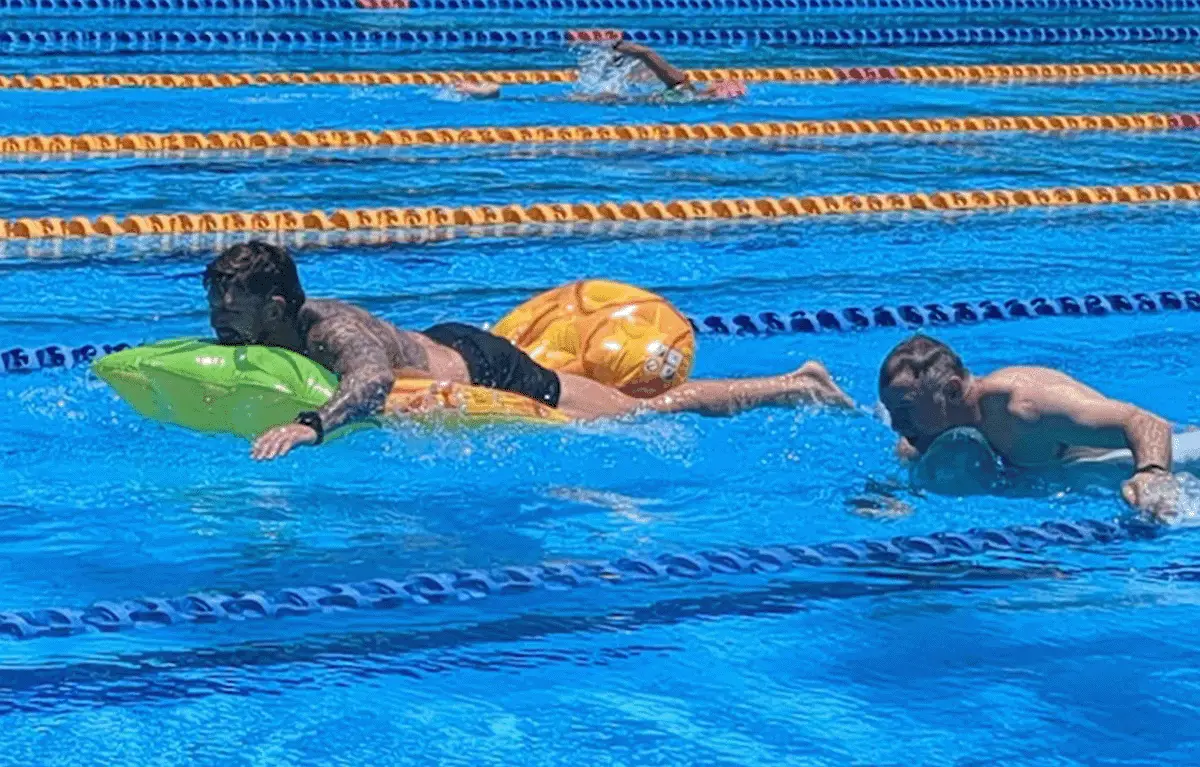 Teams blowing up pool toys before swimming relay laps in a Sunshine Coast Amazing Race